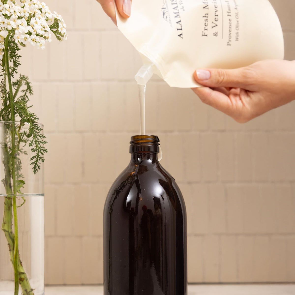 A LA MAISON pouring refill into a pump dispenser for easy reuse
