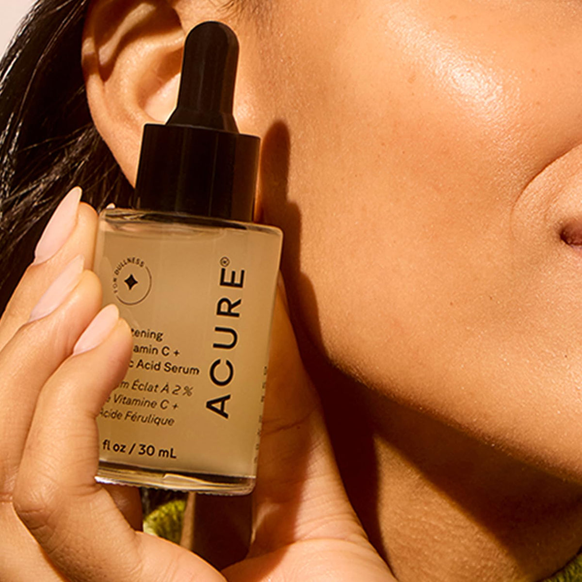 Acure serum applied to cheek to show gentle application and hydration