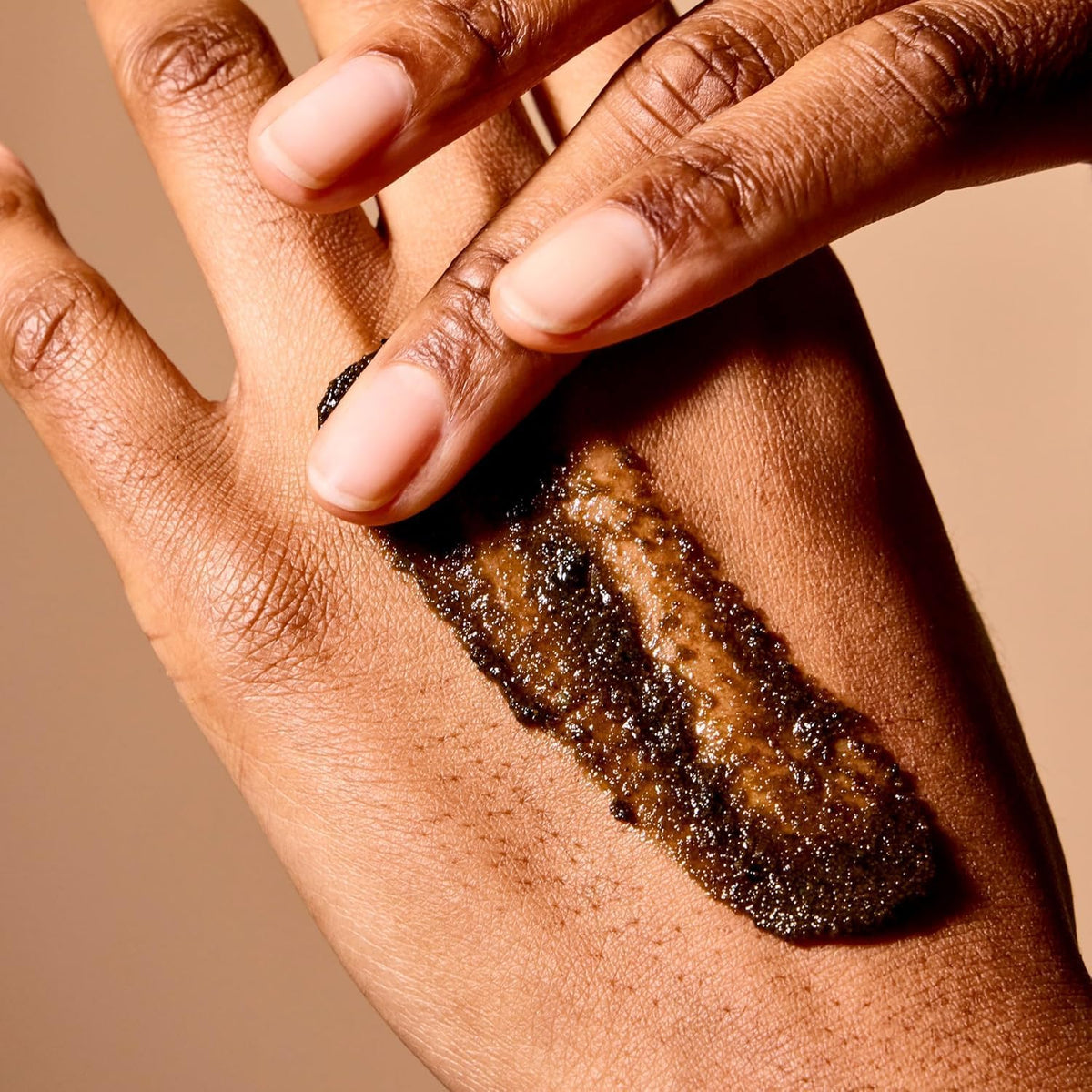 Acure hand applying scrub in shower demonstrating gentle exfoliation