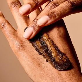 Acure hand applying scrub in shower demonstrating gentle exfoliation