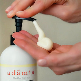Adamia bottle held beside a hand showing 15 fl oz scale and travel-friendly size