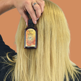 Agadir argan oil next to hand for scale showing convenient 2.25 fl oz size
