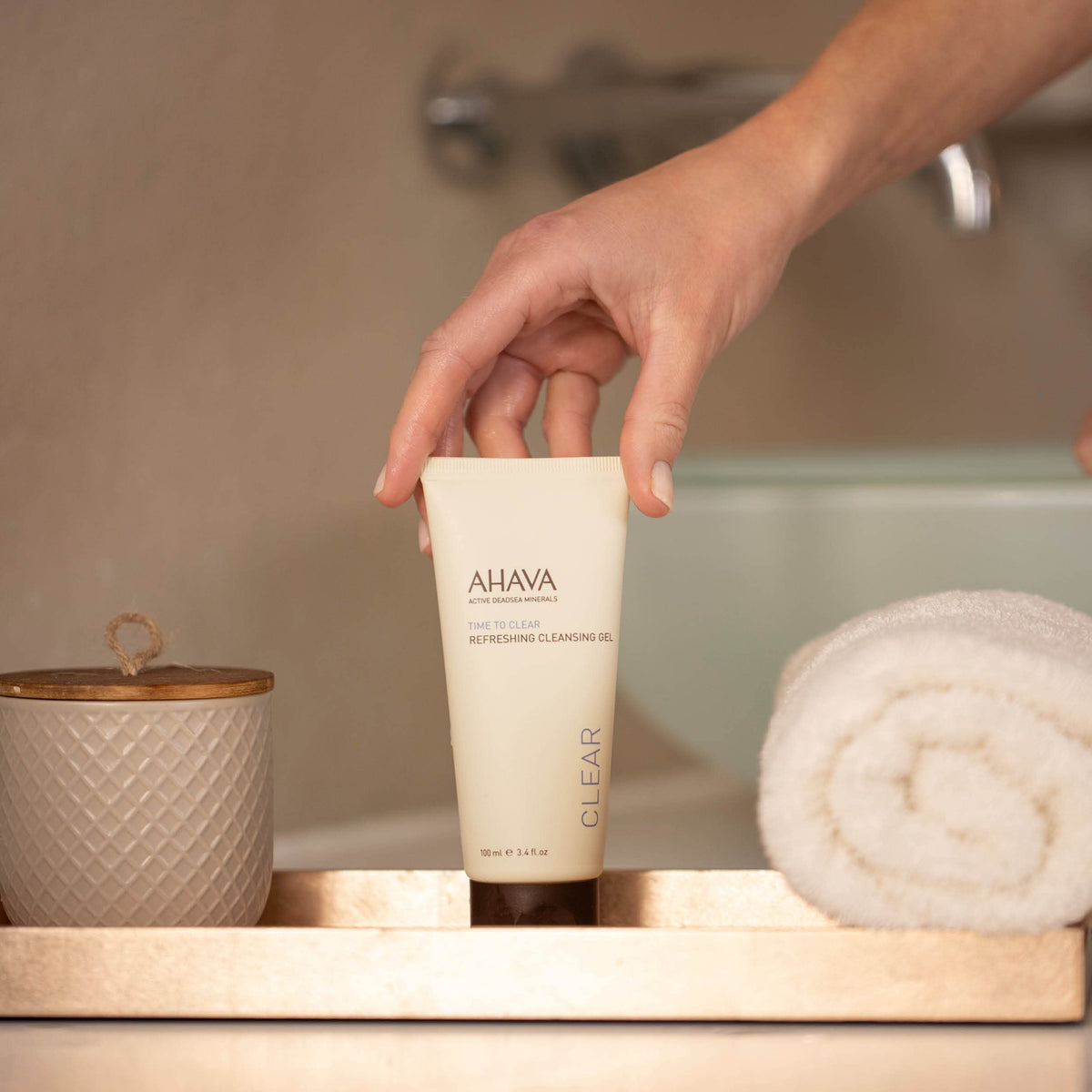 AHAVA cleanser beside hand for size comparison and easy travel benefit