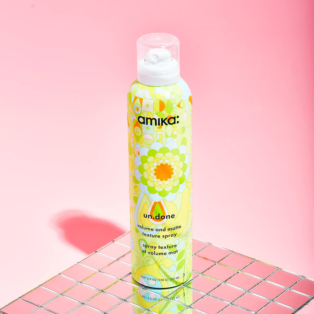 amika un.done bottle next to hand showing product scale and travel convenience