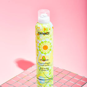 amika un.done bottle next to hand showing product scale and travel convenience