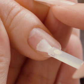 APRÉS primer 15 ml beside hand for scale, demonstrating compact salon-friendly size