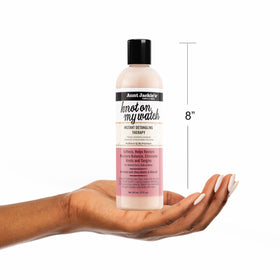 Aunt Jackie's bottle next to hand for scale showing travel-friendly 12 oz convenience