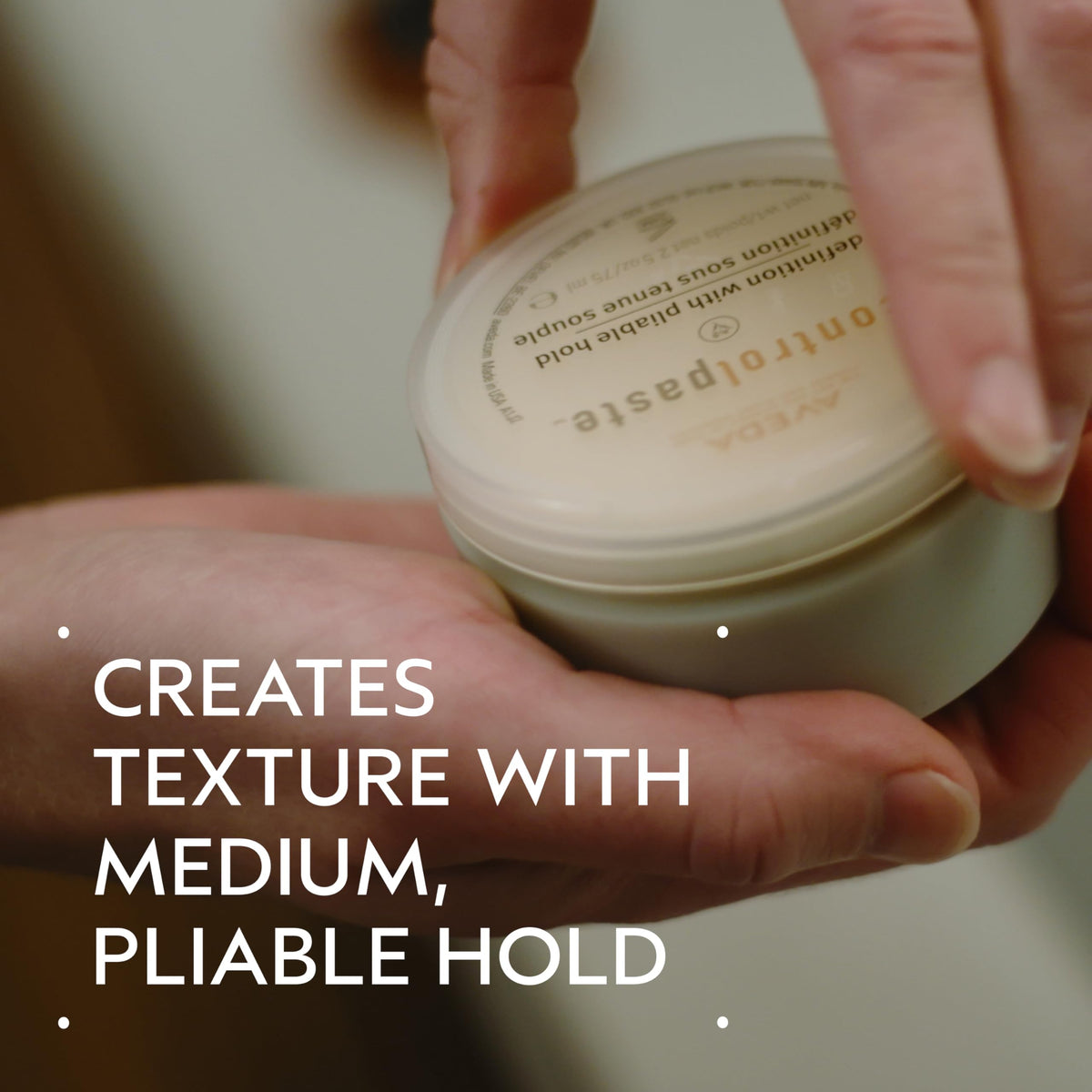 Aveda control paste close-up texture on hand showing pliable consistency