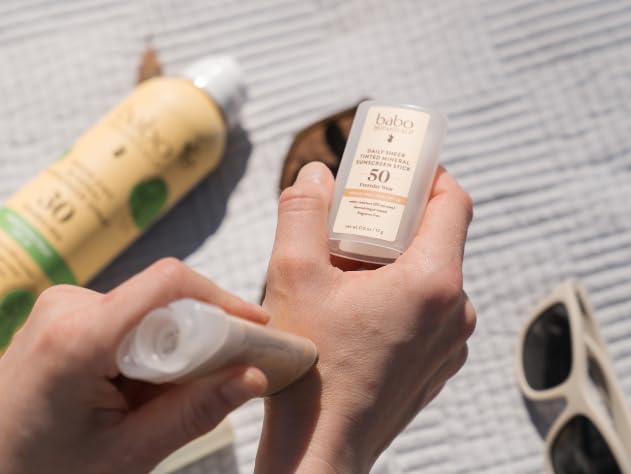 Applying Babo Botanicals tinted stick to cheek for quick coverage