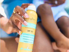 Babo Botanicals family at beach using spray for quick sun protection outdoors