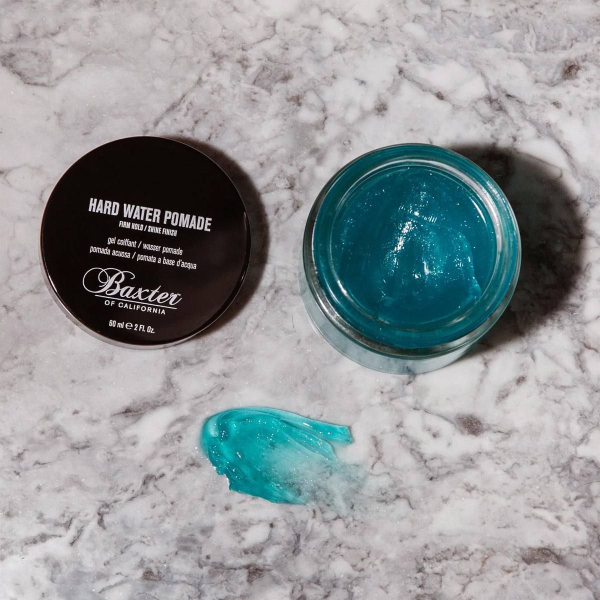 Baxter of California pomade next to travel items showing compact 2 fl oz size