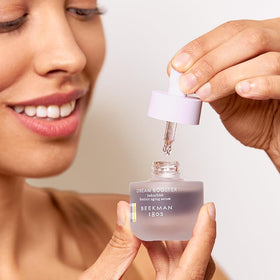 Beekman 1802 Dream Booster next to a 0.5 fl oz measure showing compact travel-friendly size