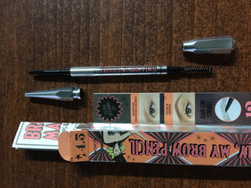 Benefit pencil held in hand to show scale and travel-friendly retractable format
