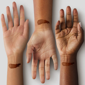 Black Radiance foundation stick held in hand to show size and travel-friendly benefit