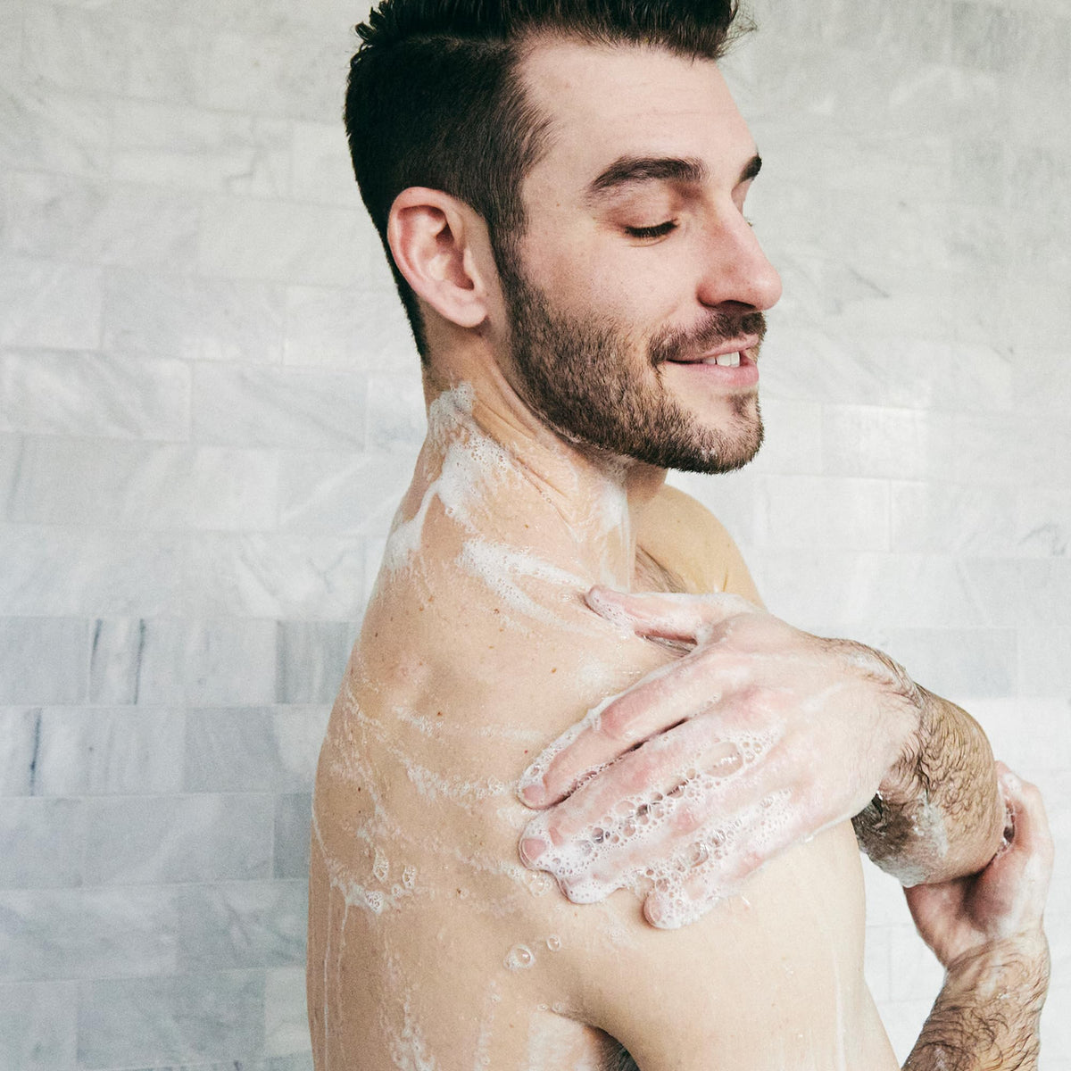 Brickell bottle in use under shower stream showing effective cleansing