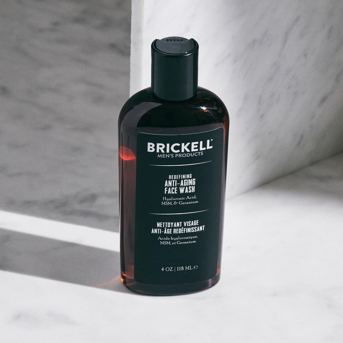 Brickell Men's Products bottle in hand showing 4 oz scale for travel-friendly convenience