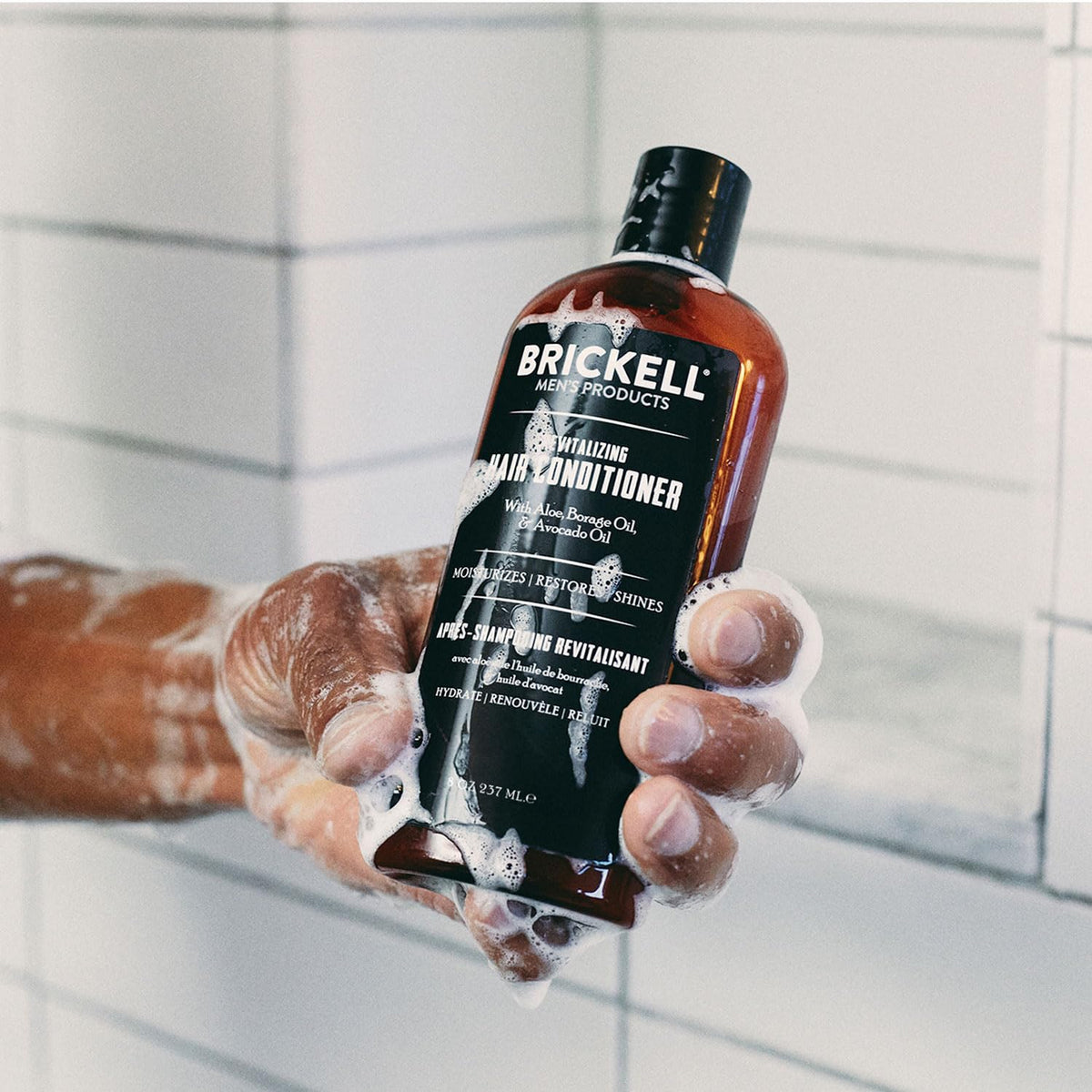 Brickell conditioner in use under shower, demonstrating smoother, manageable hair benefit
