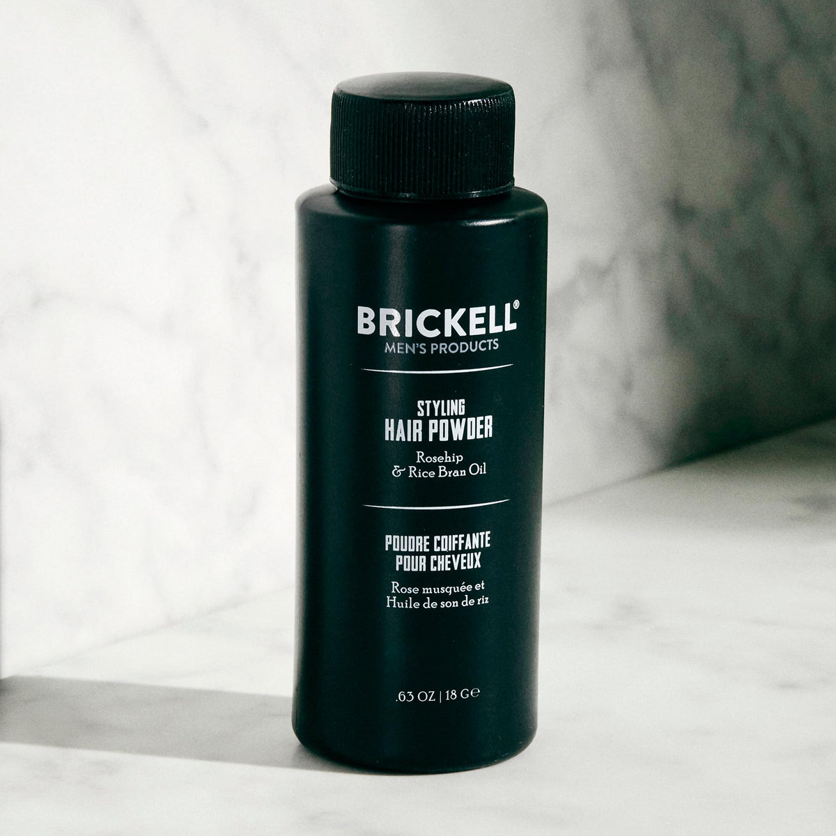 Brickell Men's hair powder pouring from open top demonstrating controlled application