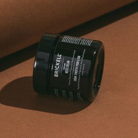 Brickell Men's Products next to a measuring tape displaying the 2-ounce size for travel-ready grooming
