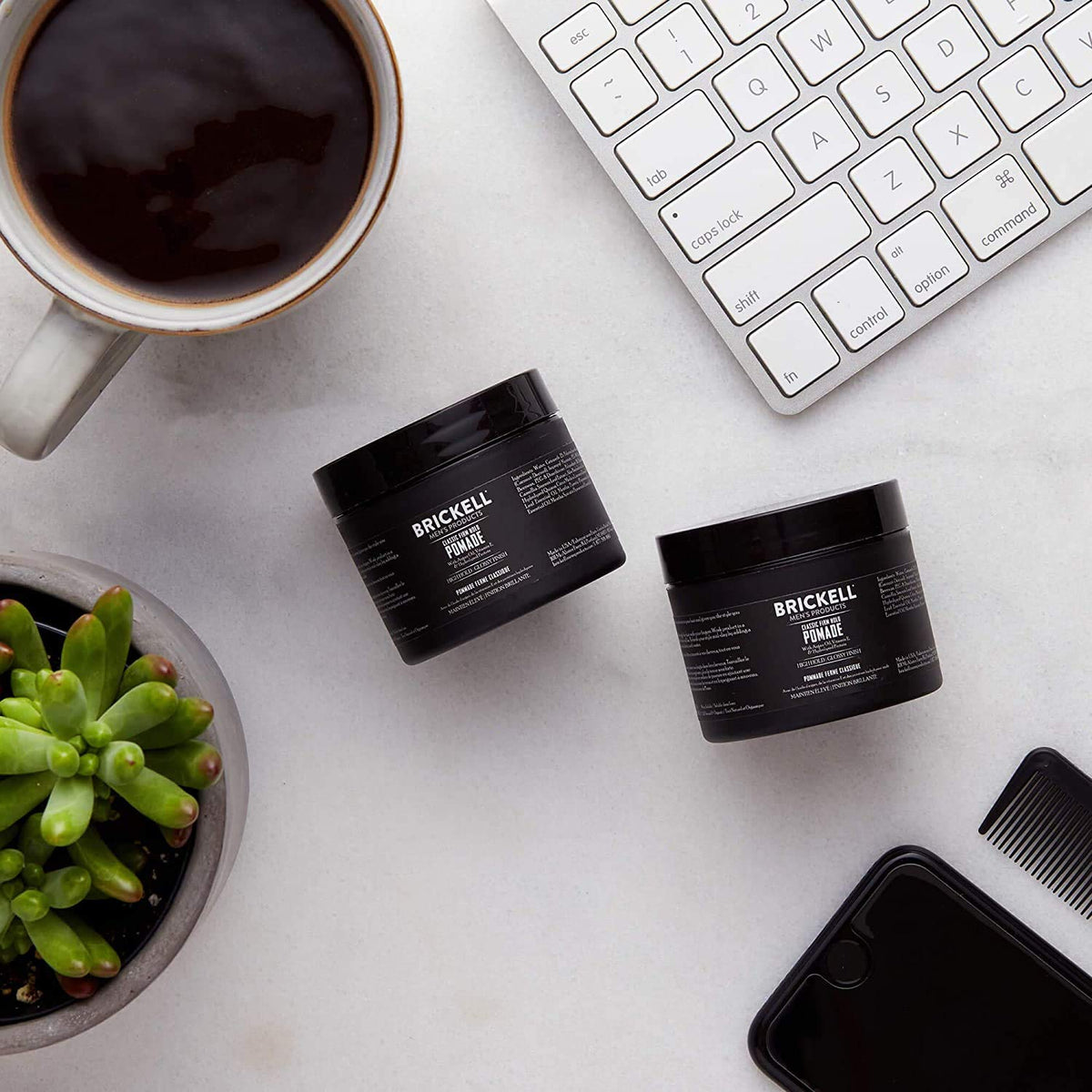 Brickell Men's pomade held in hand showing 2 oz scale and portability