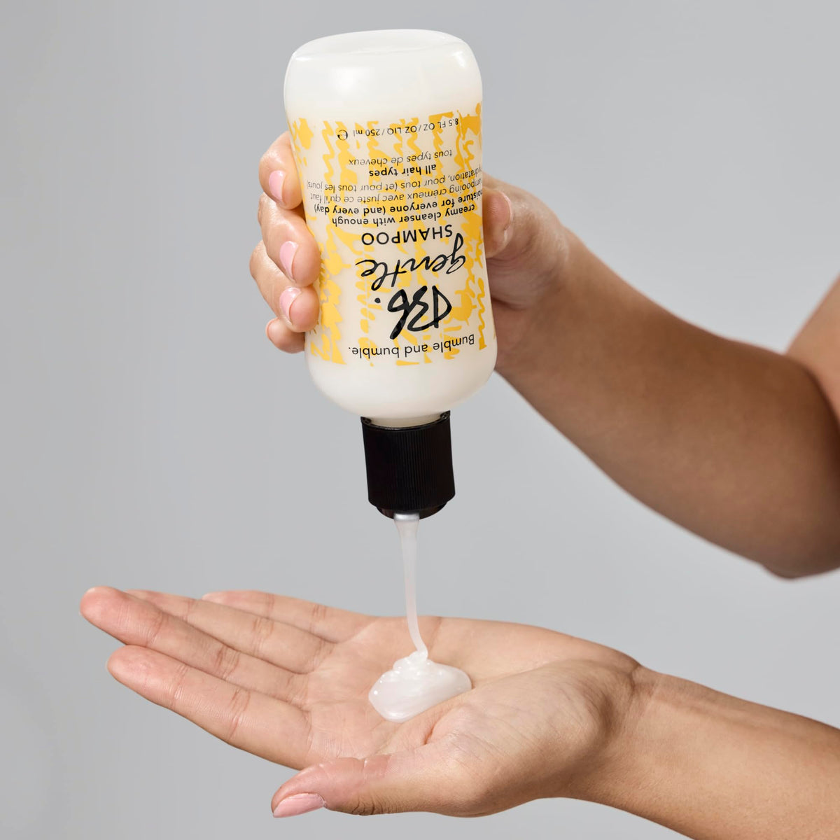 Bumble and bumble bottle next to dispenser pump to show scalable home refill convenience