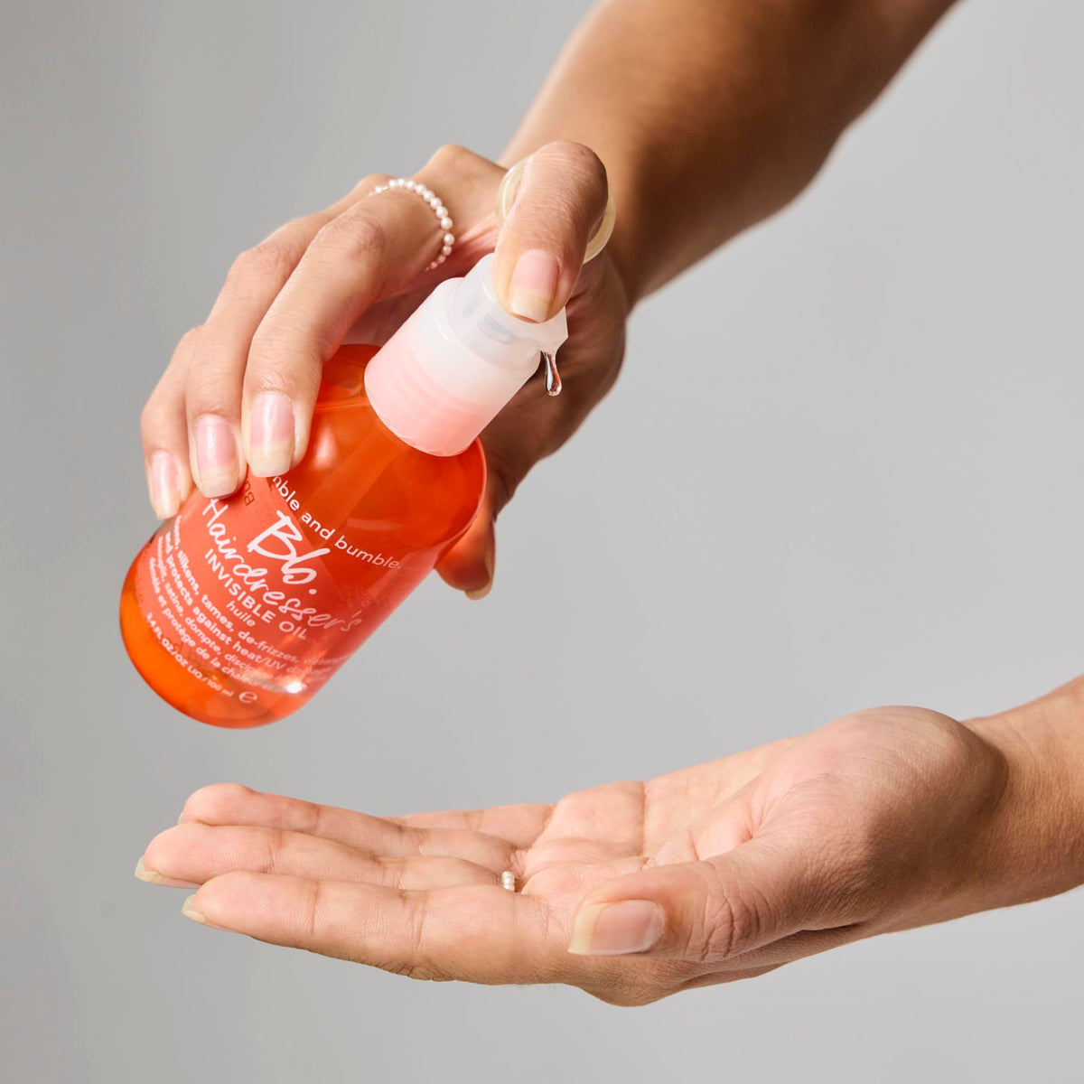 Bumble and bumble drops on a single hair strand reducing frizz and smoothing cuticle