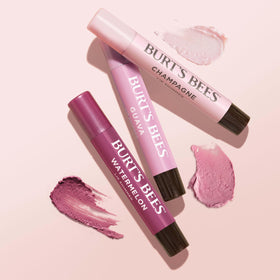 Burt's Bees application over lipstick in hand adding glossy dimension and hydration