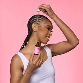 Camille Rose serum applied to hairline with fingertip, demonstrates targeted use
