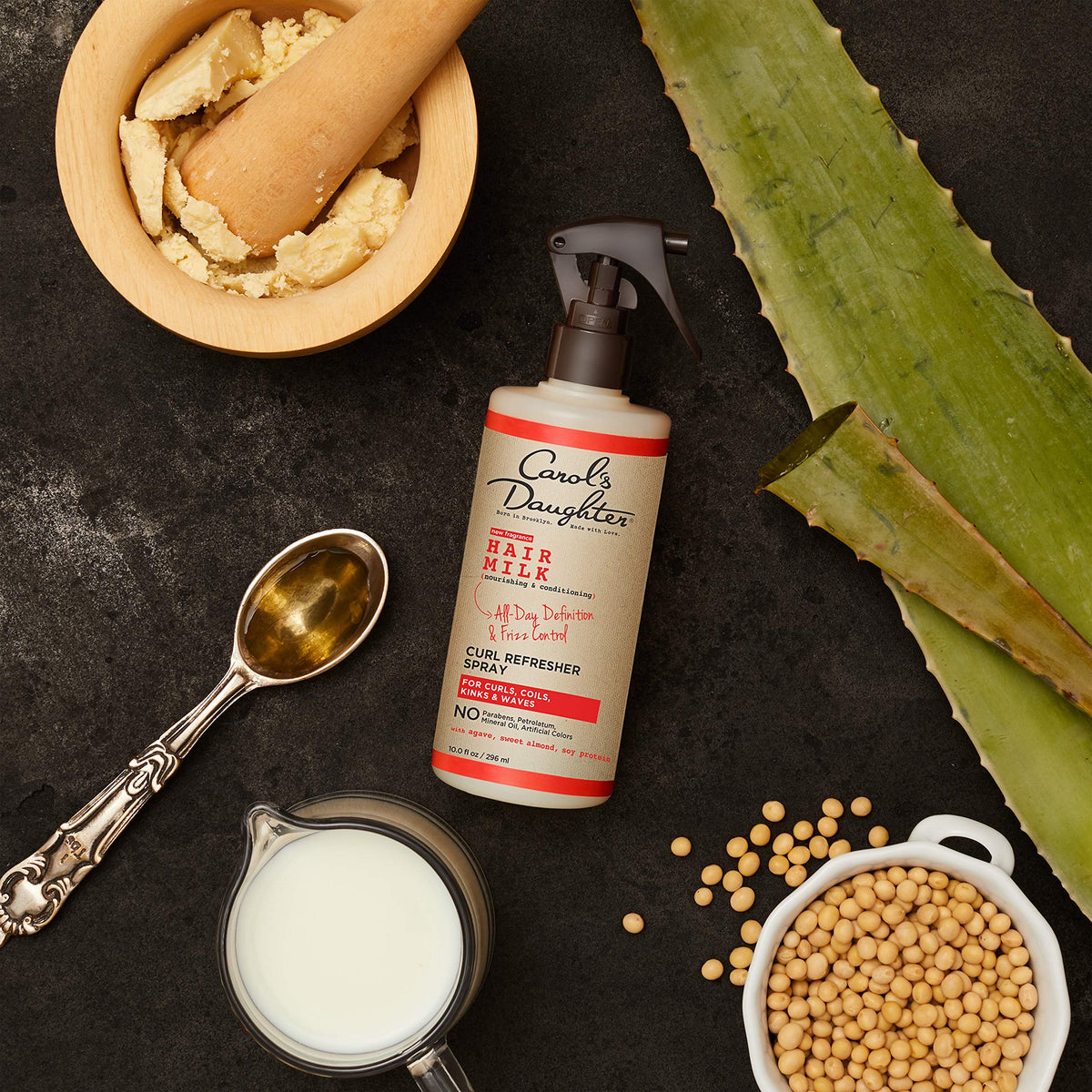 Carol's Daughter spray being applied to curls to refresh definition and reduce frizz