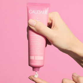 Caudalie 60 mL jar next to hand for true size and travel-friendly benefit