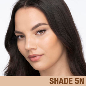 Charlotte Tilbury bottle next to everyday items showing compact size and travel convenience