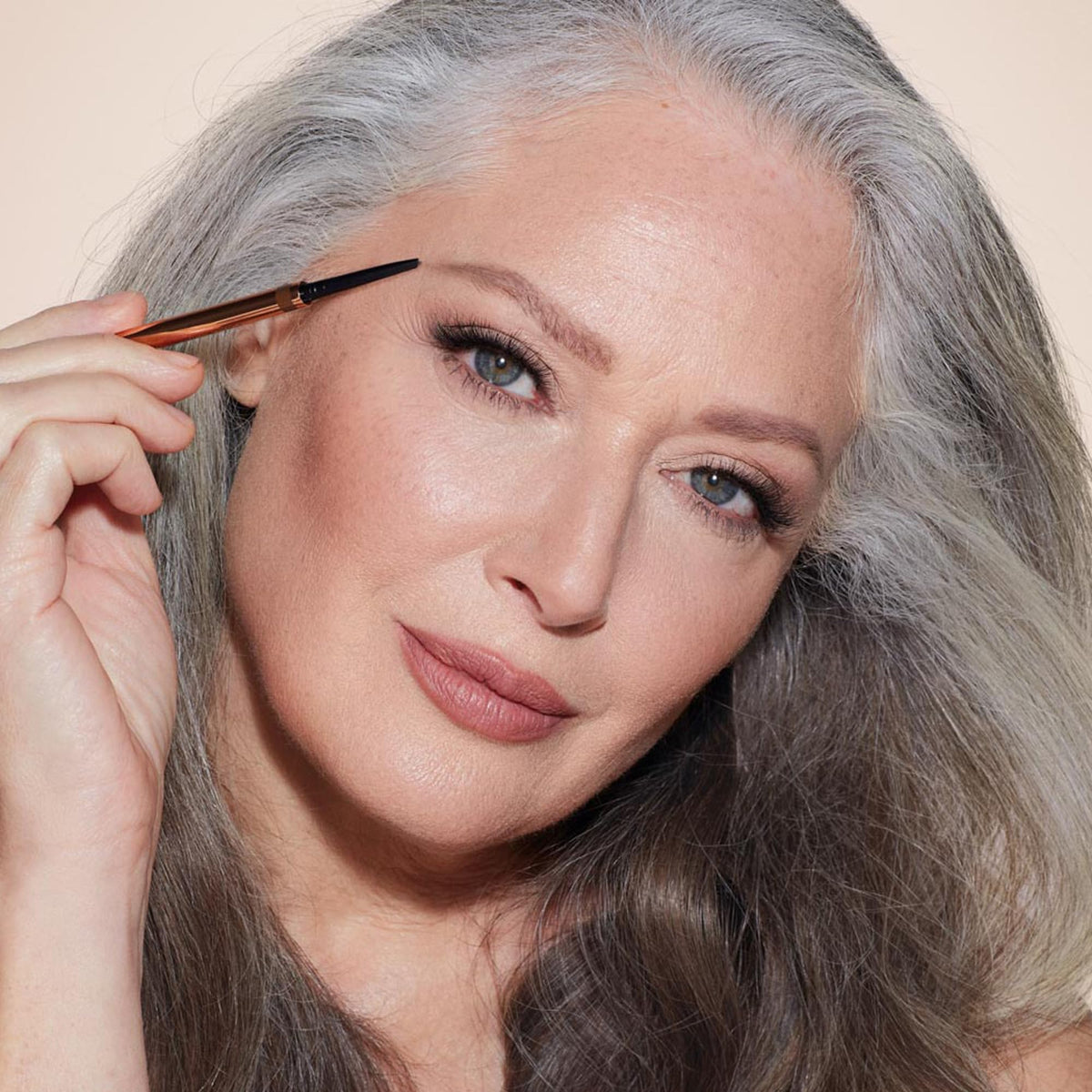 Charlotte Tilbury Brow Cheat scale next to fingers showing compact size for travel benefit