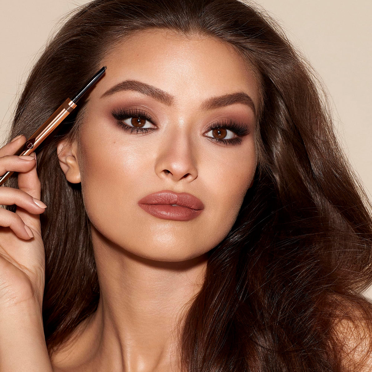 Charlotte Tilbury pencil in hand to show scale and travel-friendly convenience