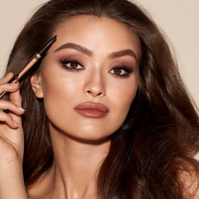 Charlotte Tilbury pencil in hand to show scale and travel-friendly convenience