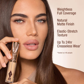 Charlotte Tilbury applying concealer under eye to conceal dark circles