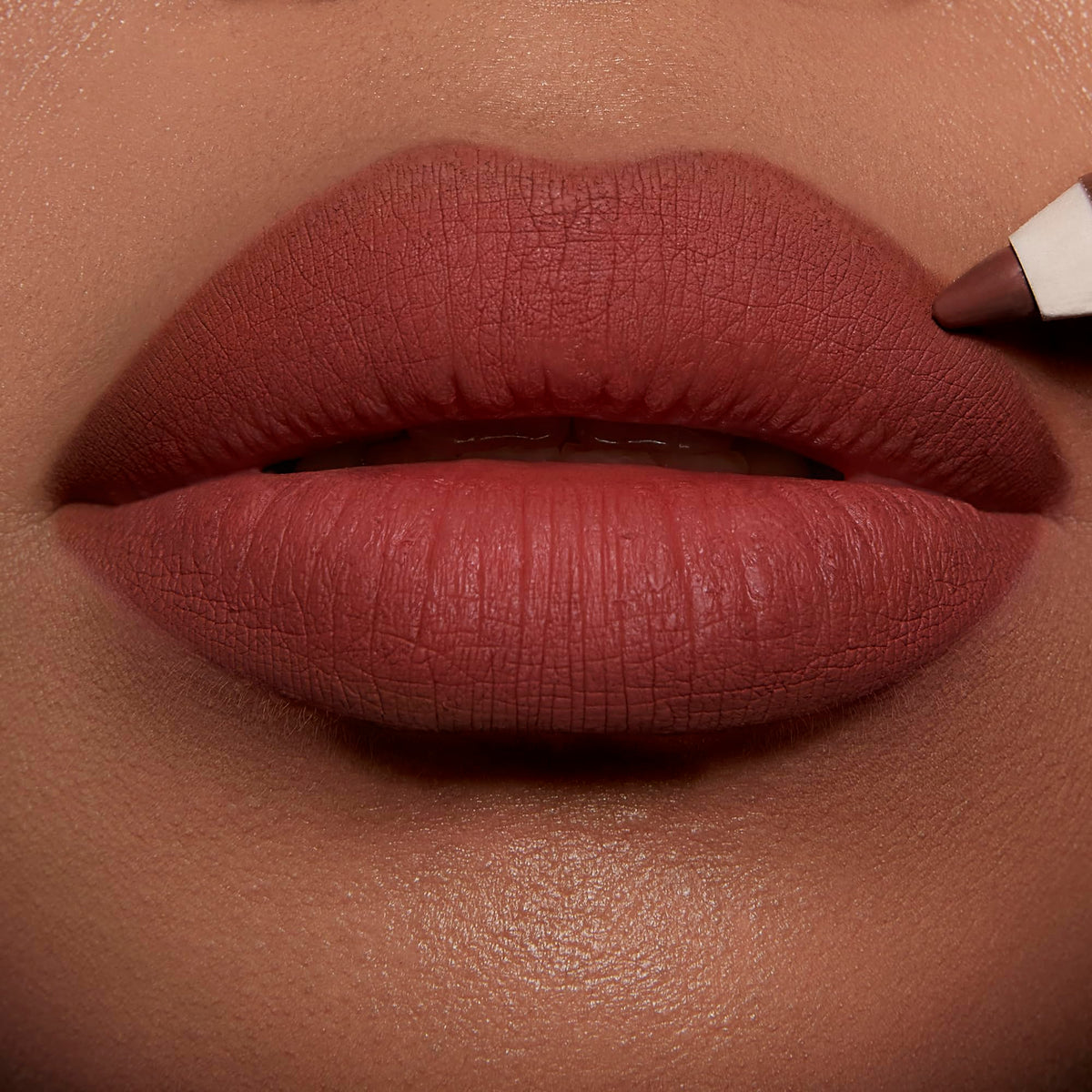 Charlotte Tilbury swatches on skin displaying warm caramel-red payoff for flattering color match