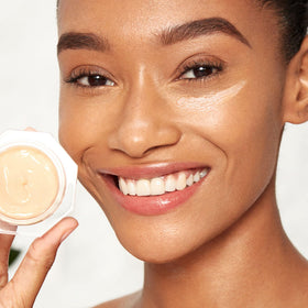 Charlotte Tilbury on bathroom vanity with mirror and makeup, suggests prep-for-makeup benefit