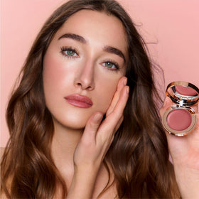Charlotte Tilbury compact held by fingers to show scale and portable, on-the-go convenience