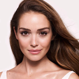 Charlotte Tilbury next to common items showing 40ml size and travel-friendly benefit