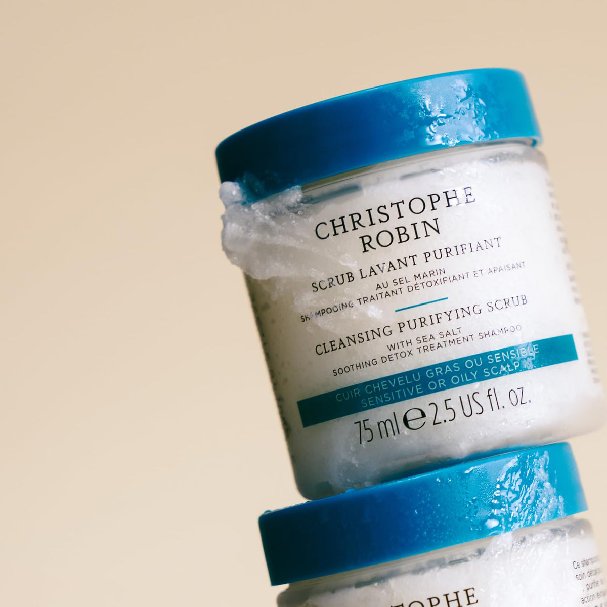 75ml Christophe Robin tube next to a hand to show compact travel-friendly size