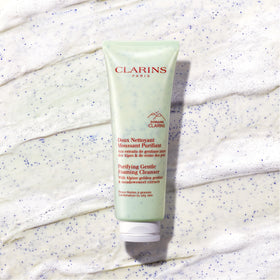 Clarins cleanser bottle beside a coin for size comparison and portability benefit