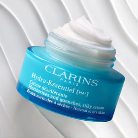 Clarins 1.7 oz jar beside a coin to show true size and portability