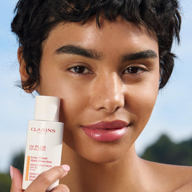 Clarins size comparison next to common items showing compact travel-friendly sunscreen