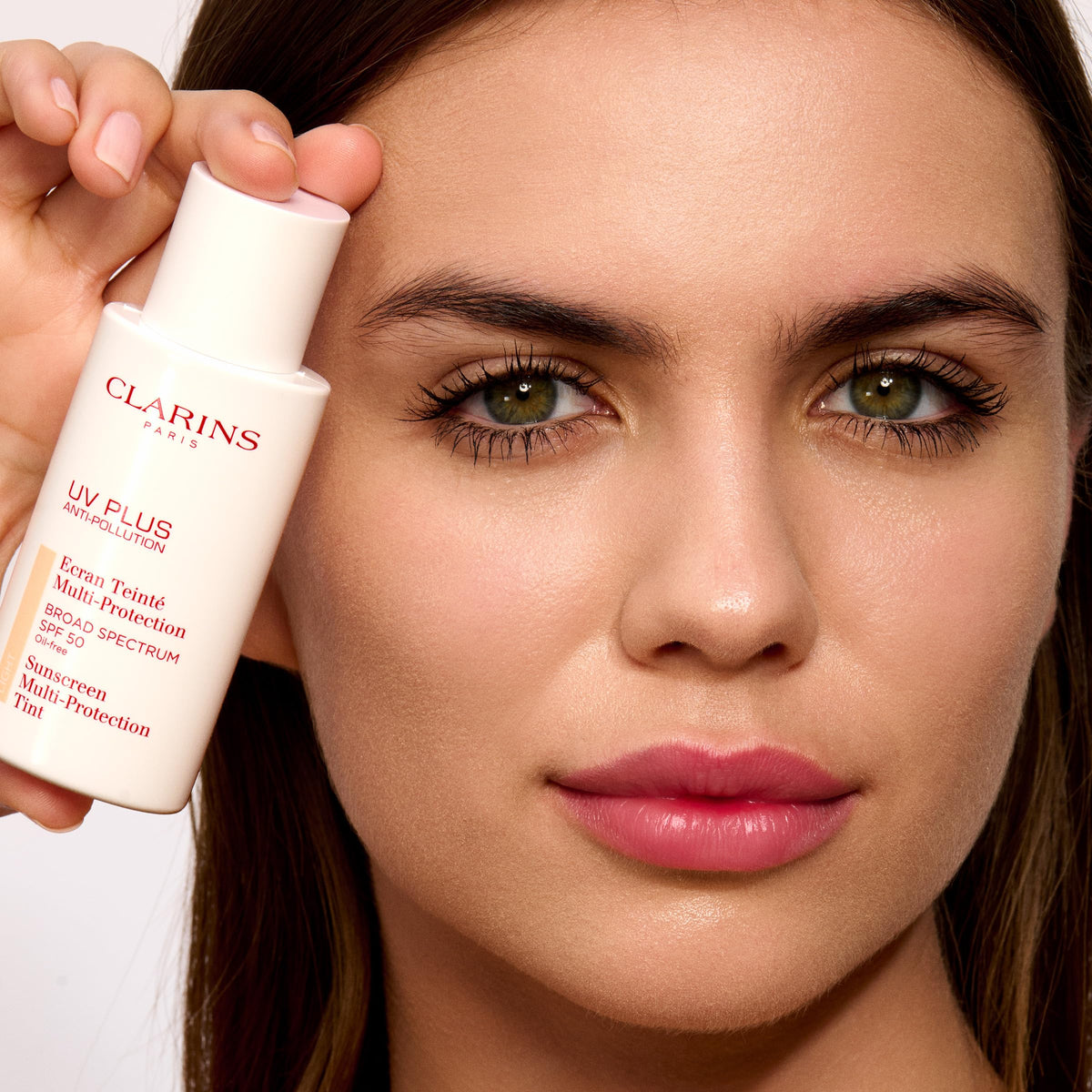 Clarins UV Plus tube beside everyday items showing travel-friendly size benefit