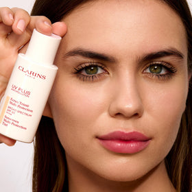 Clarins UV Plus tube beside everyday items showing travel-friendly size benefit