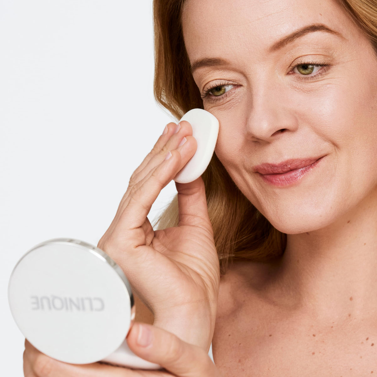 Clinique compact being applied on face in a mirror lifestyle scene for quick touch-up benefit