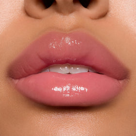 ColourPop gloss on model lips demonstrating sheer baby pink glossy effect