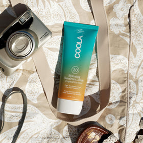 COOLA bottle on beach towel conveying reef-compliant sun protection