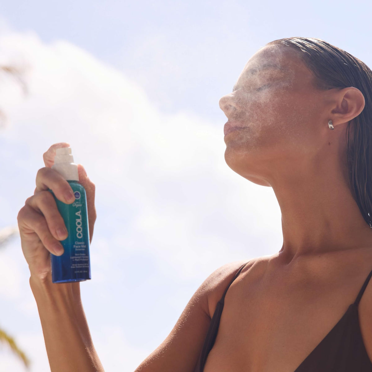 COOLA face mist in use outdoors on person refreshing skin and providing on‑the‑go protection benefit