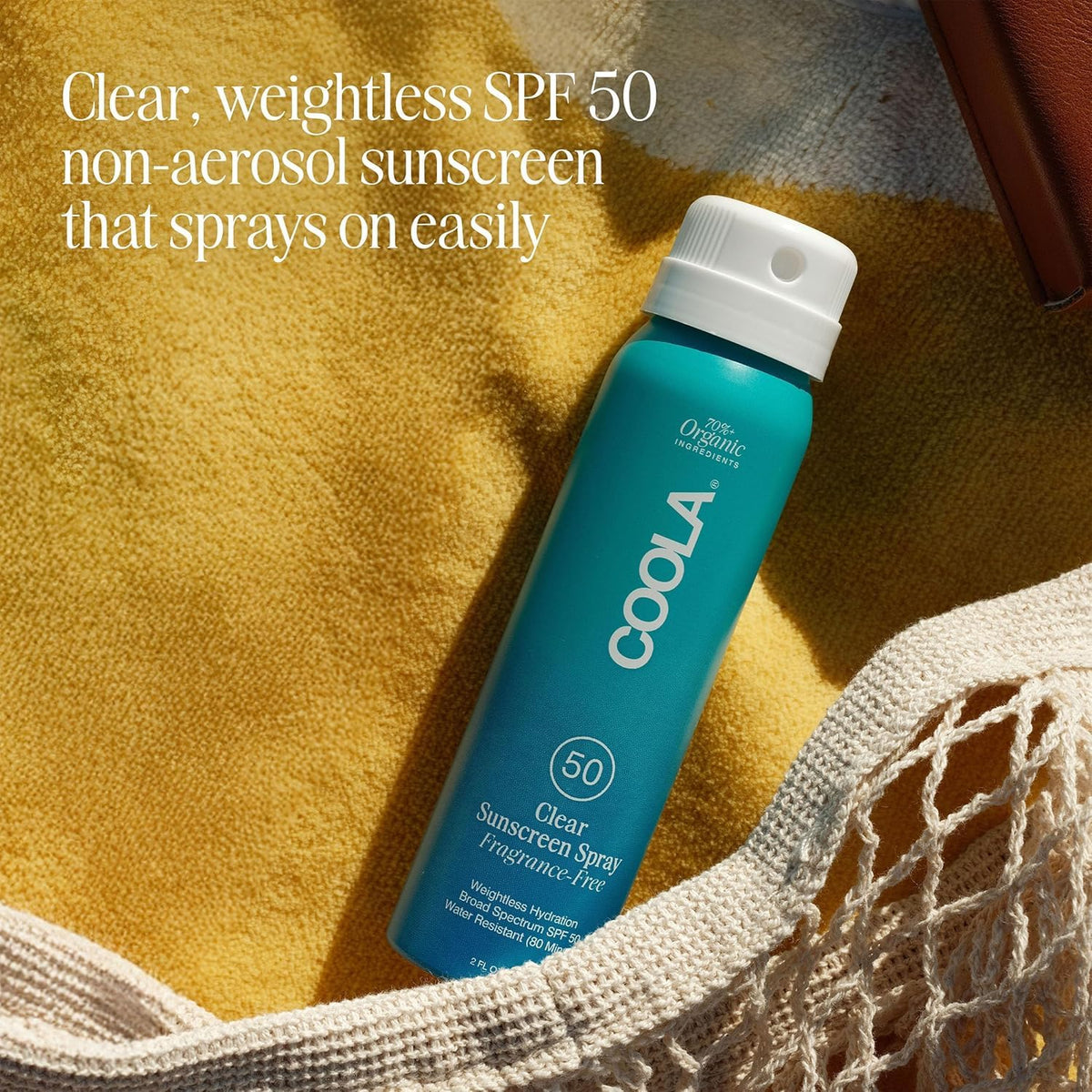 COOLA bottle held in hand showing 2 fl oz scale for travel-ready convenience